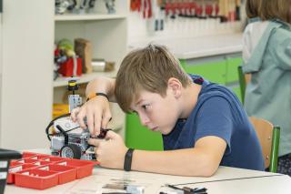 volle Konzentration beim Bau eines tierischen Roboters Ein Junge baut konzentriert an einem tierischen LEGO-Roboter